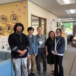 Executive Director Minh-Duc Nguyen (center right) and Ron Choi (center) rely on the work of volunteers to keep Helping Link running. Photo by Drew Dotson/Renton Reporter