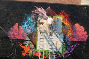 Spray paint mural artist Jeff Weirdo (@weirdocult on Instagram) works on the latest downtown mural on Williams Avenue, which is in partnership with Wizards of the Coast, a Renton-based game company famous for Dungeons & Dragons and Magic: The Gathering. Photo by Bailey Jo Josie/Sound Publishing