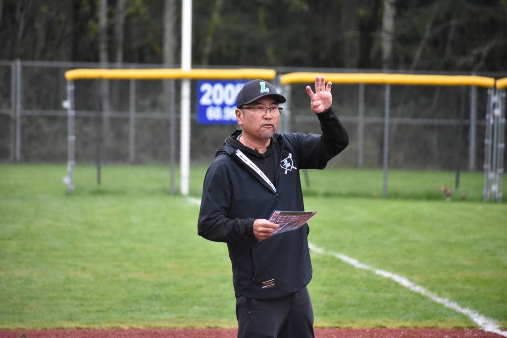 Joon Huh gives a sign from the third-base line. Ben Ray / The Reporter