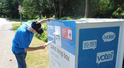 A man places his ballot into the drop box. Bailey Jo Josie/Sound Publishing